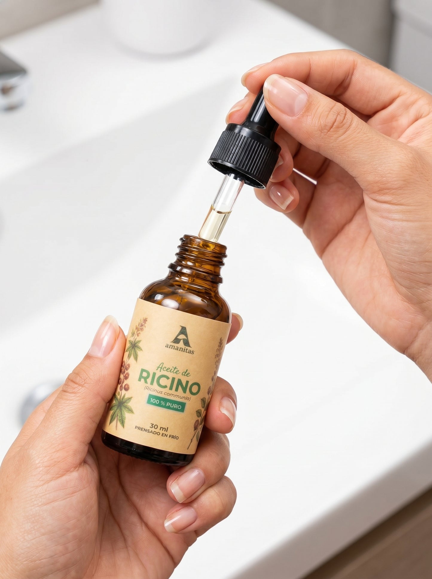 Persona aplicando Aceite de Ricino 100% puro Amanitas utilizando el gotero de precisión sobre la palma de la mano. El frasco de vidrio ámbar de 30 ml muestra claramente la etiqueta con ilustración botánica, destacando su uso práctico y profesional en rutinas de cuidado capilar y piel.