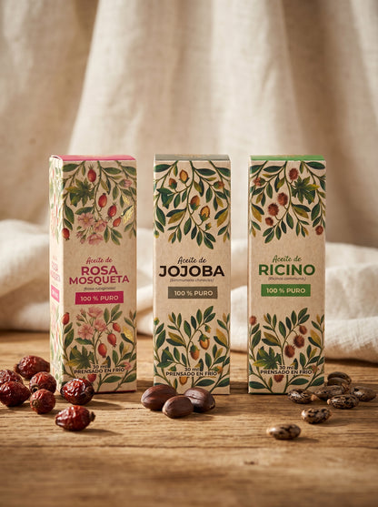Set de tres aceites naturales de la marca Amanitas: Rosa Mosqueta, Jojoba y Ricino. Los empaques de cartón con diseño botánico están dispuestos sobre una superficie de madera, mostrando la presentación premium y ecológica de la colección de aceites prensados en frío.