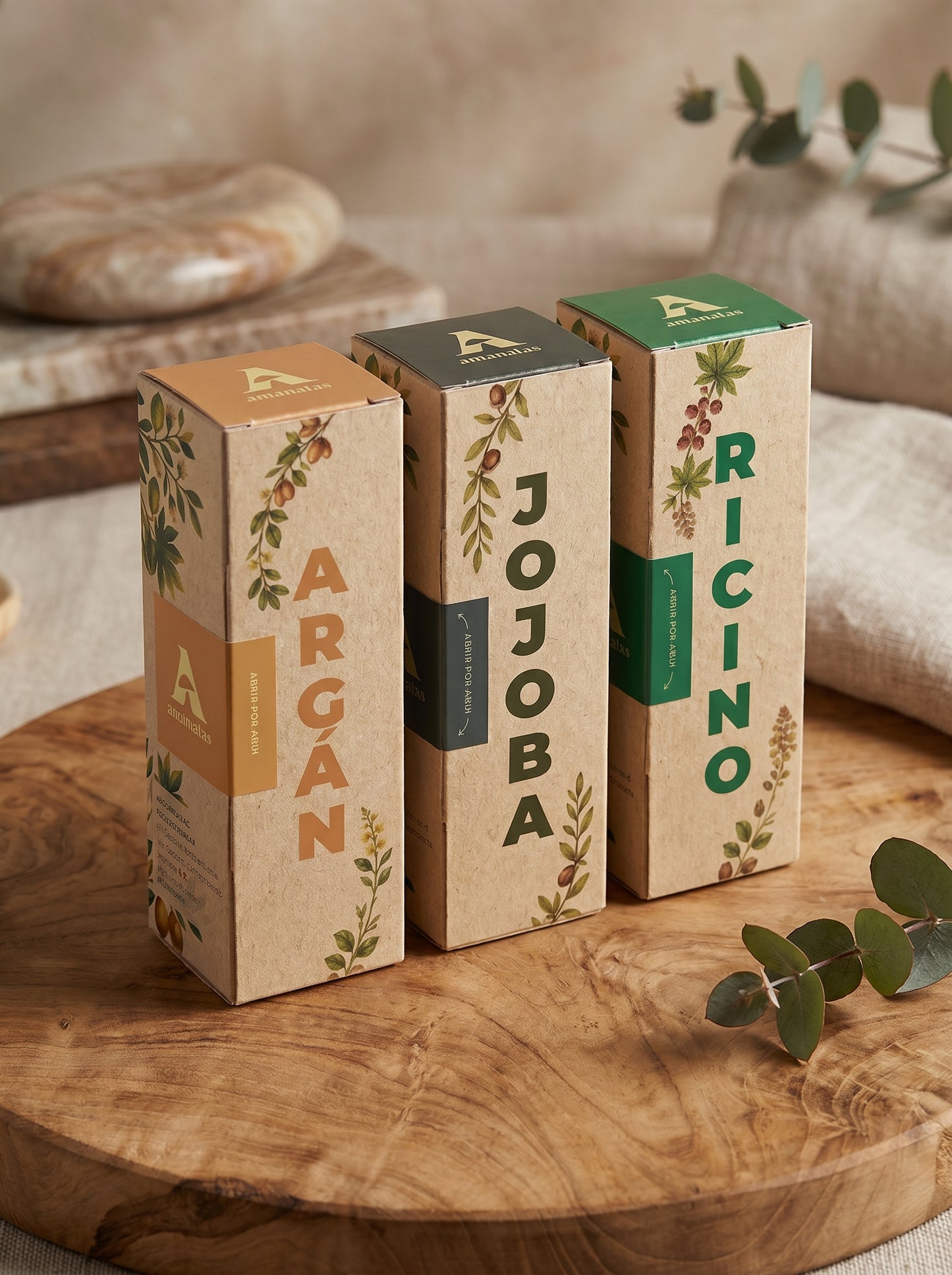Set de tres aceites naturales de la marca Amanitas: Argán, Jojoba y Ricino. Los empaques de cartón con diseño de ilustraciones botánicas muestran la presentación premium y ecológica de la colección de aceites prensados en frío sobre una superficie de madera.